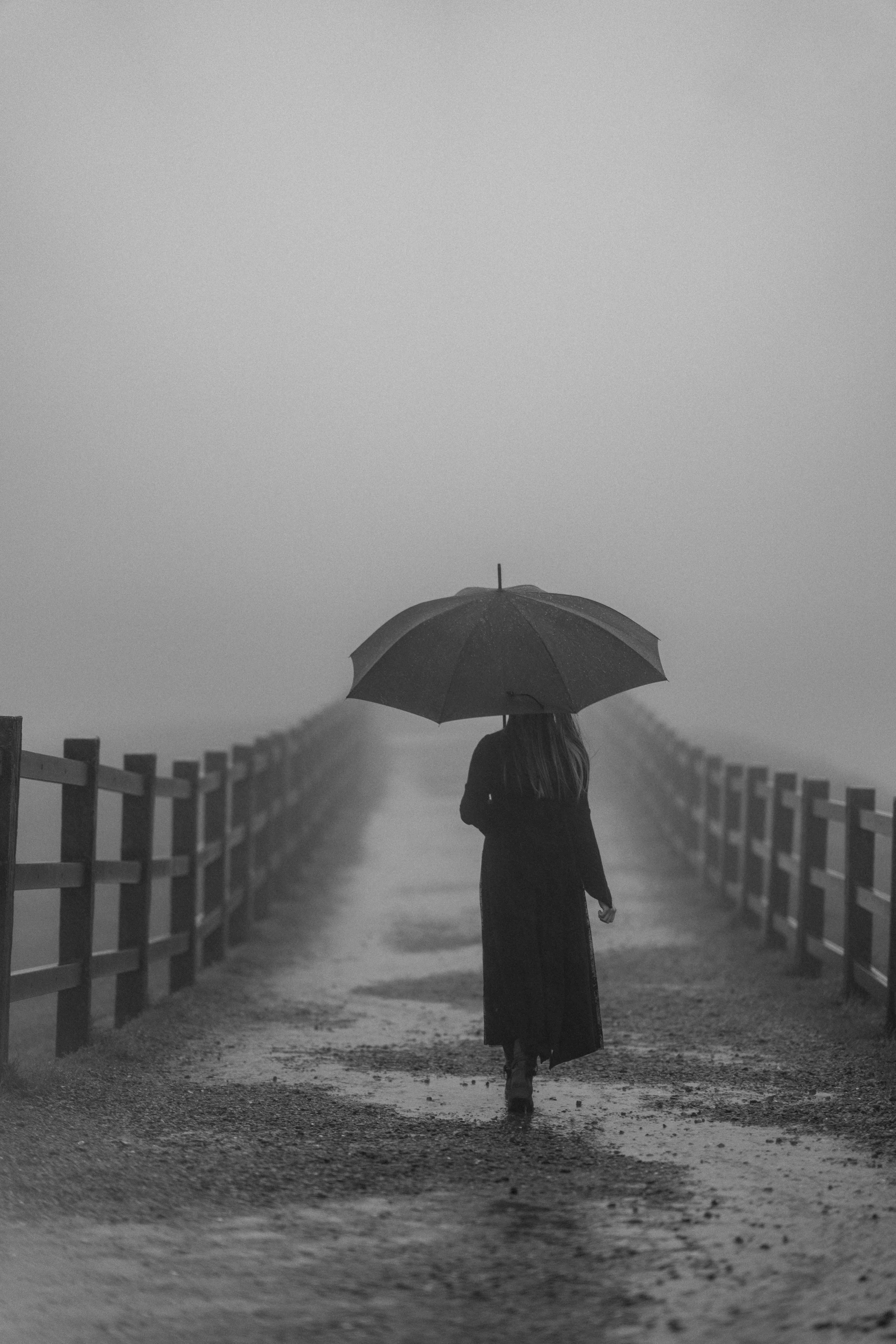 灰霧雨天道路上撐傘前行的人物